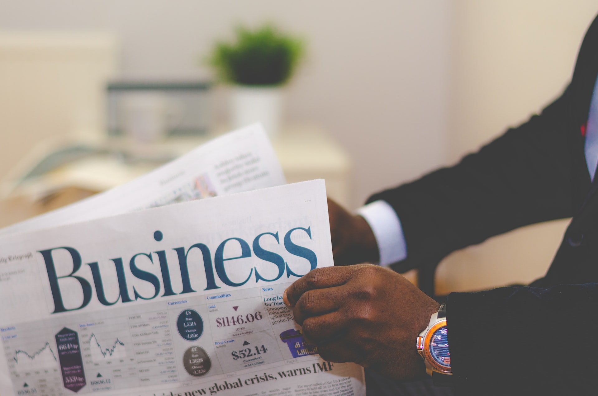 Person wearing suit holding business section of newspaper